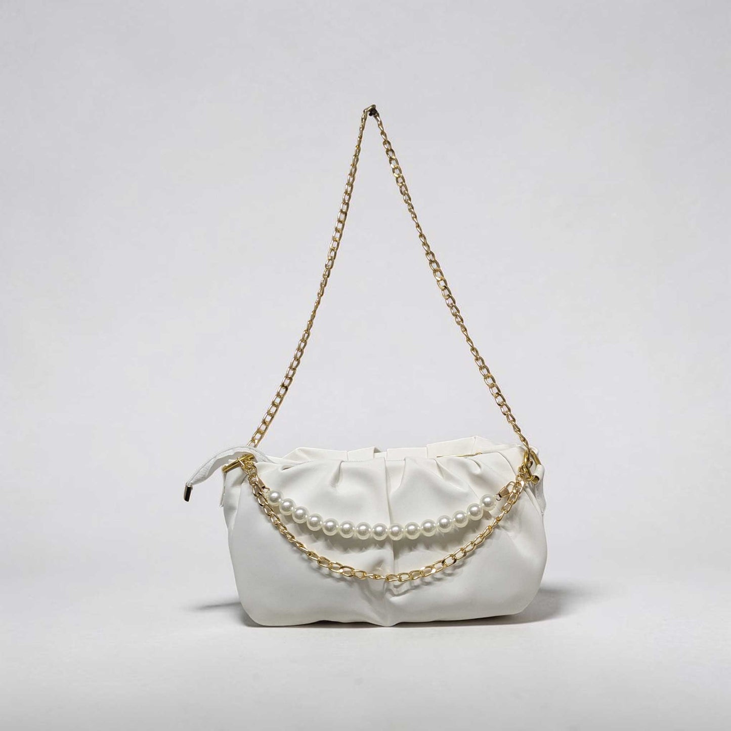 White handbag with a gold chain and pearl details on a light gray background