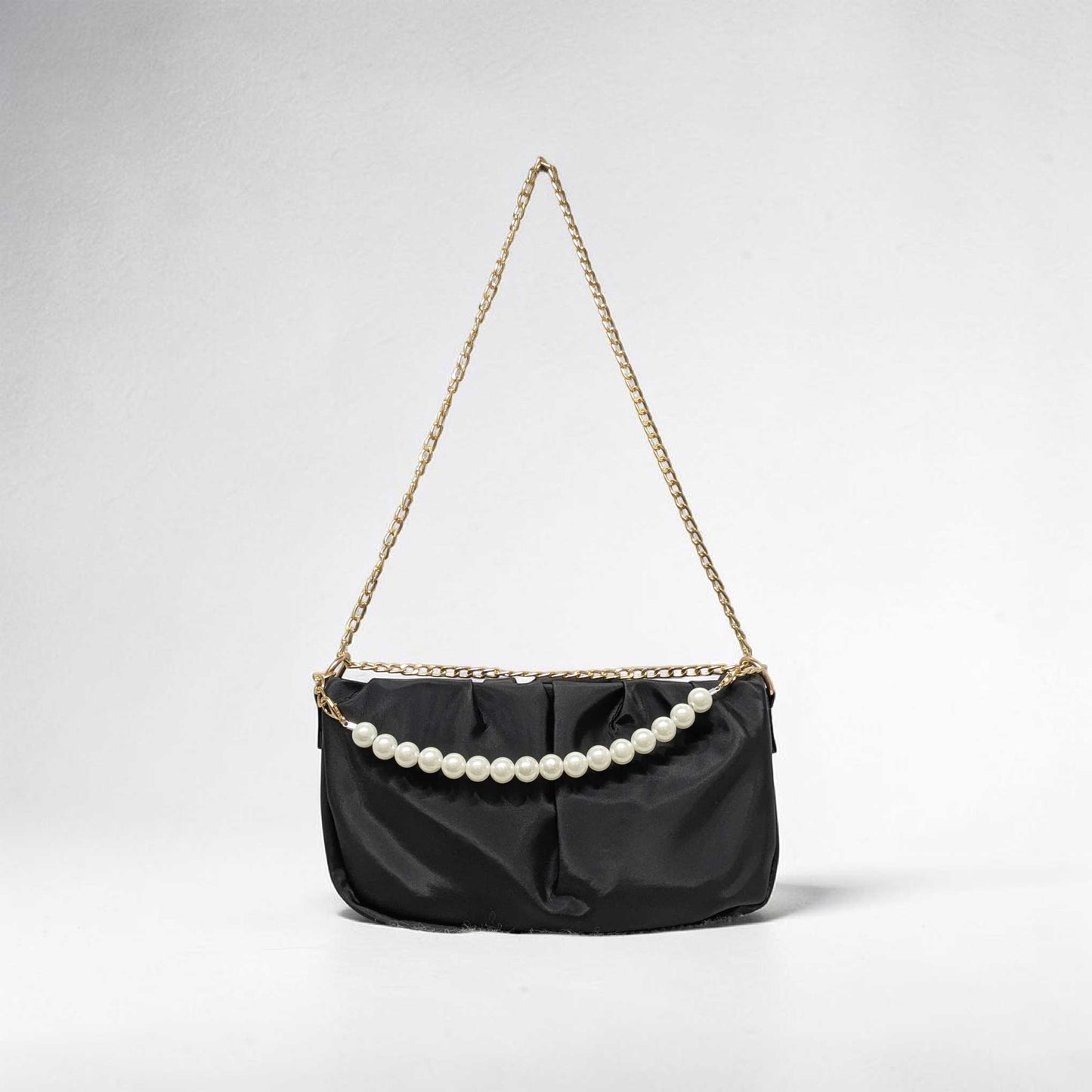 Black handbag with pearl embellishments on a light gray background