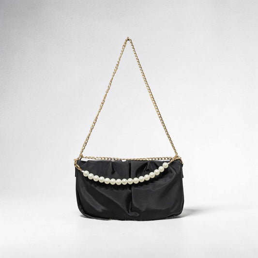 Black handbag with pearl embellishments on a light gray background
